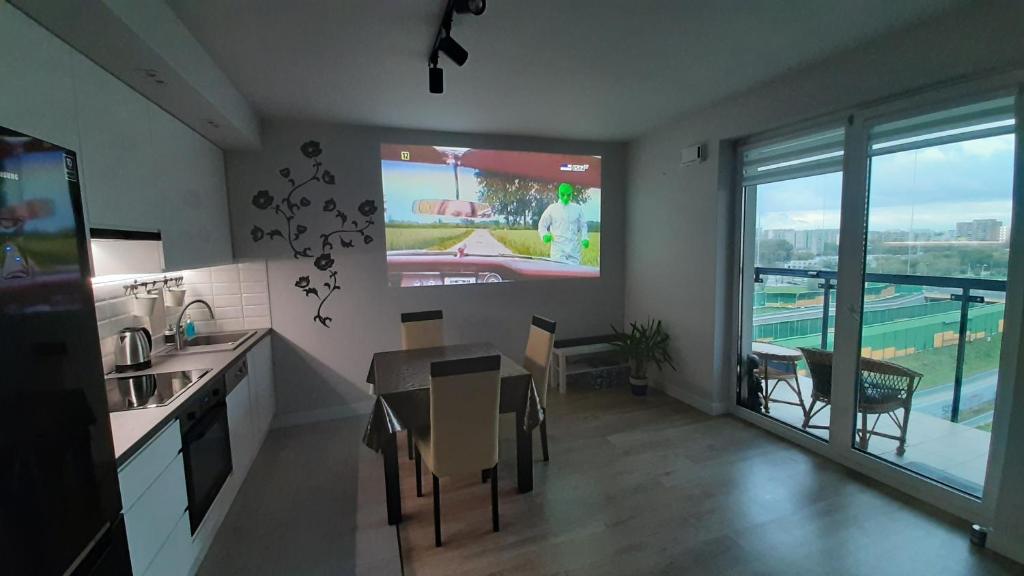 a kitchen with a tv and a table with chairs at Apartament Pełka in Warsaw