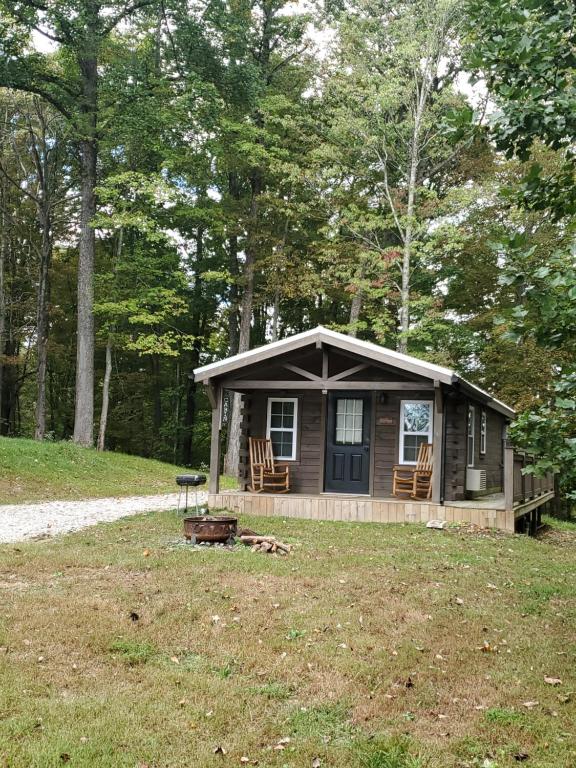 una cabina nel bosco con portico e sedie di The Riverside - An Amish Built Log Cabin a Genoa