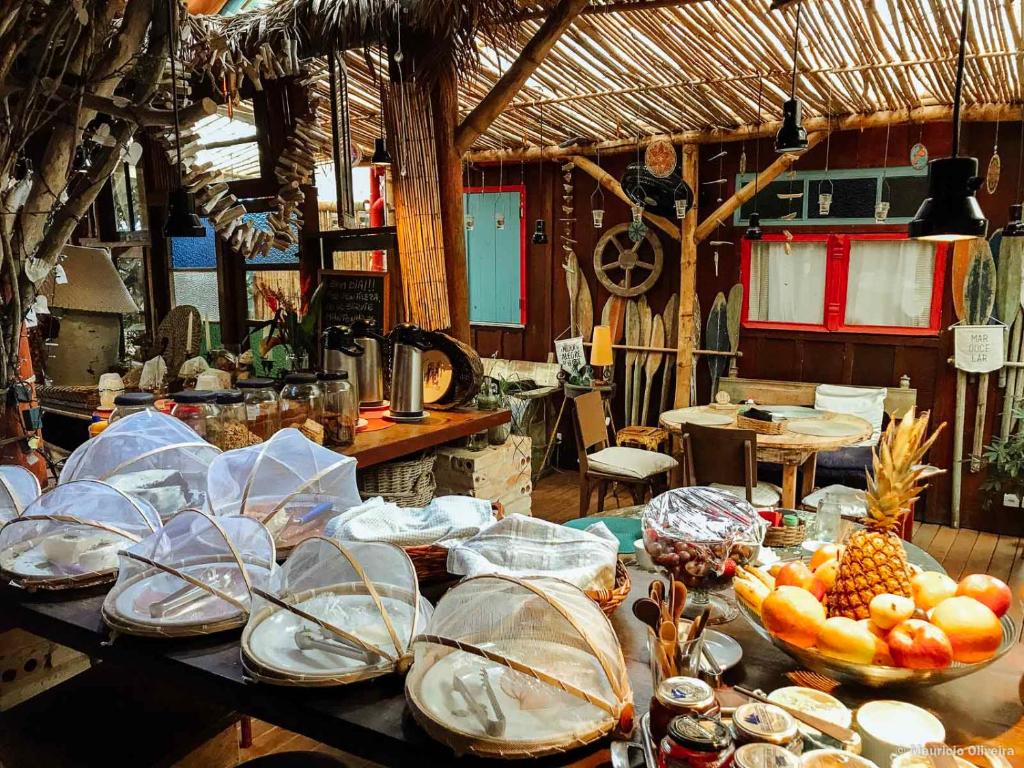 a table with plates and bowls of fruit on it at Pousada das Meninas in Ilha do Mel