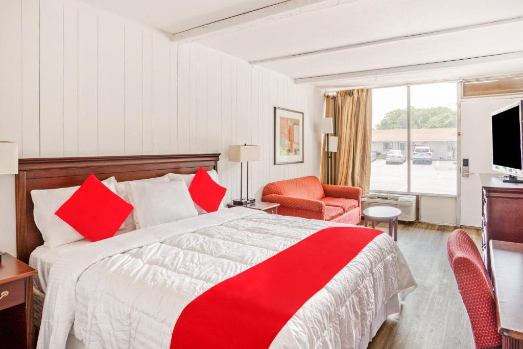 um quarto de hotel com uma cama grande e uma cadeira vermelha em OYO Inn Kernersville em Kernersville