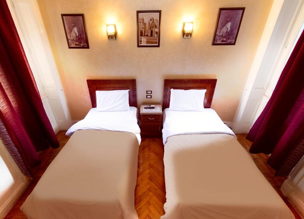 2 Betten in einem Zimmer mit roten Vorhängen in der Unterkunft Minerva Grand Boutique in Kairo