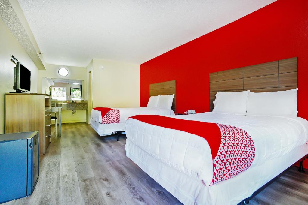 a hotel room with two beds and a red wall at OYO Hotel Decatur I-285 The Perimeter in Decatur