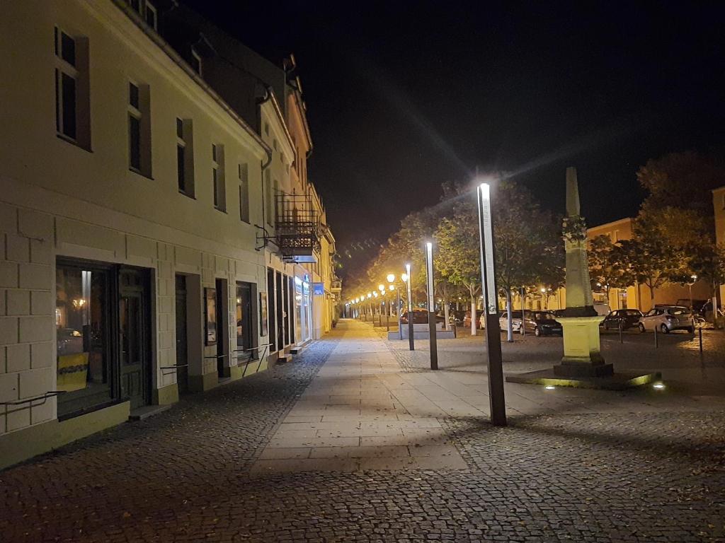 a city street at night with street lights and a building at Ferienwohnung Hainbuche Lübben im Spreewald in Lübben