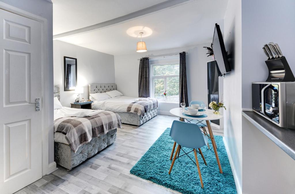 um quarto com 2 camas e uma mesa com uma cadeira azul em Grey Stone Studio Apartments em Halifax