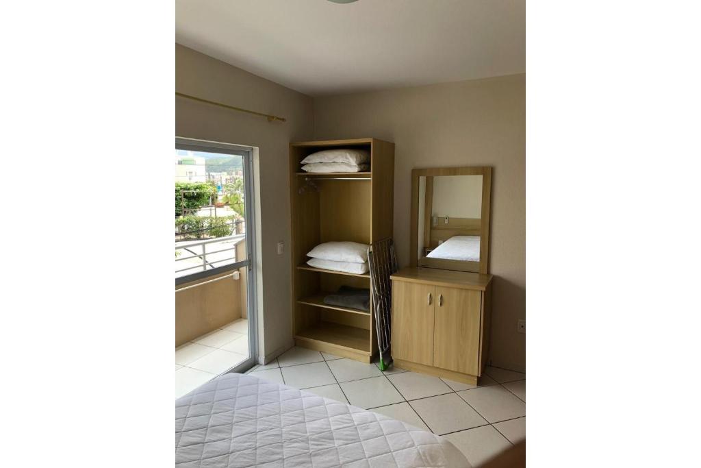 um pequeno quarto com uma cama e um espelho em Residencial Gaivotas 05 - 1 Quartos - Completo 30m da praia em Florianópolis