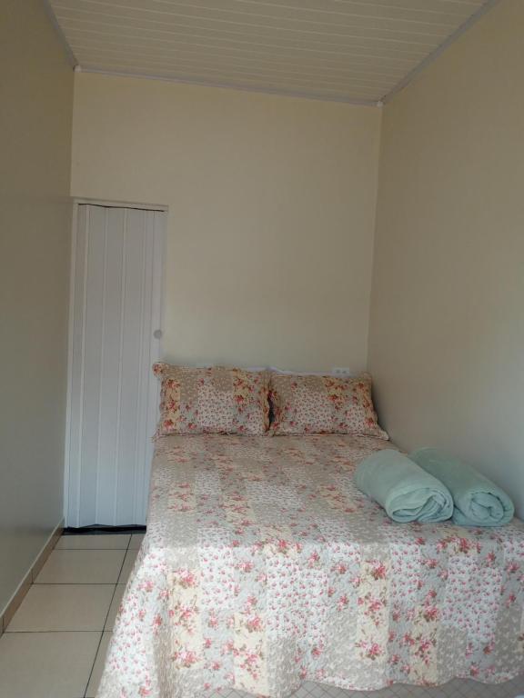 een slaapkamer met een bed met een bloemenbed en kussens bij Quarto Suíte independente da casa com garagem in Carolina