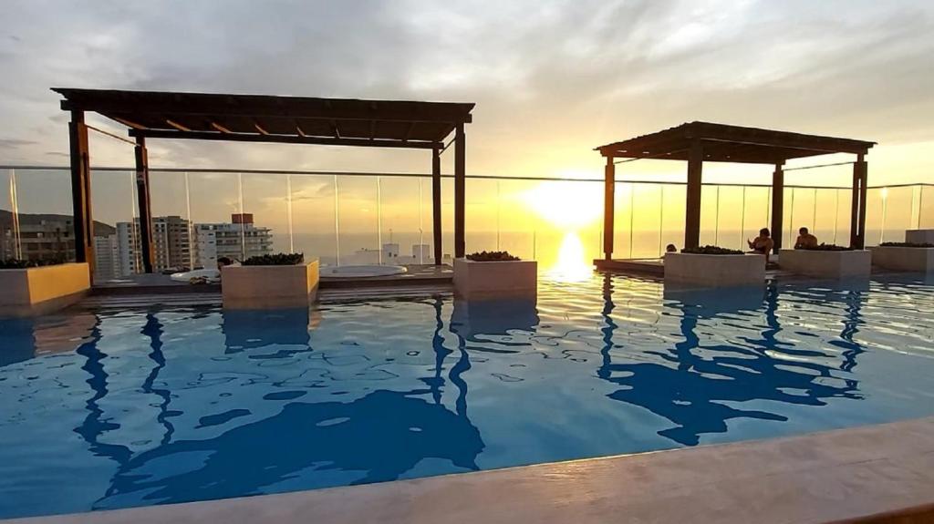 a swimming pool on the roof of a building with the sunset at New Apartment Reserva del Mar 1421 Santa Marta ocean view in Santa Marta