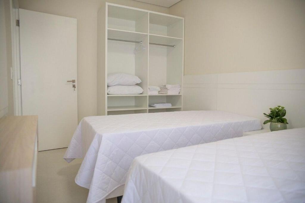 duas camas num quarto branco com prateleiras brancas em Residencial Gaivotas 14 - 2 Quartos - Melhor localização Ingleses Prox Mercado farmácia em Florianópolis