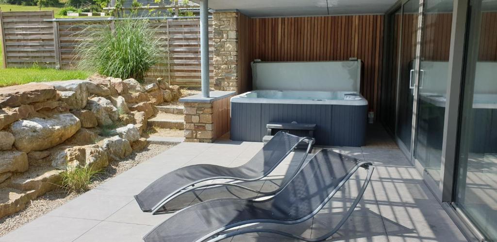 a patio with a bench and a tub in a yard at Gite Kooa Prestige in Theux