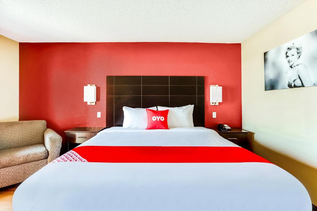 a hotel room with a large bed with a red wall at OYO Hotel Tyler Northwest Mineola Hwy in Tyler