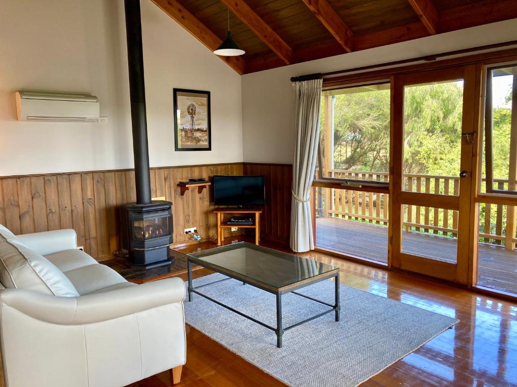a living room with a couch and a table and a stove at Daysy Hill Country Cottages in Port Campbell