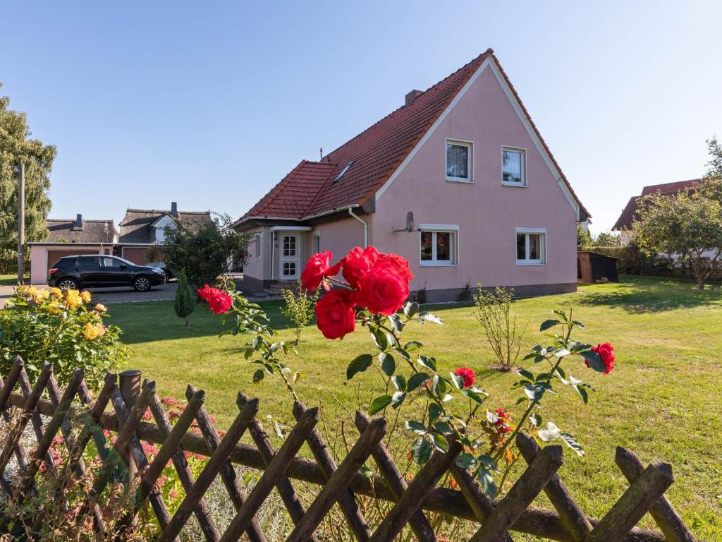 a pink house with a fence and red roses at Cozy Farmhouse in Benenden with Terrace in Teßmannsdorf