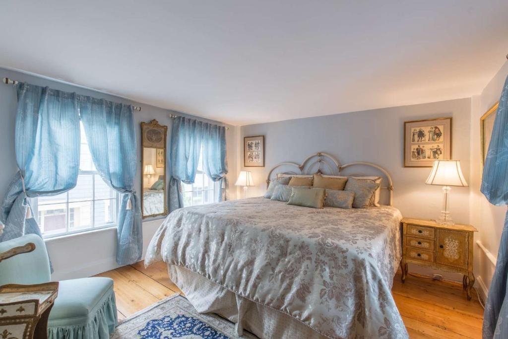 Schlafzimmer mit einem großen Bett und blauen Vorhängen in der Unterkunft Brackett Cottage in Marblehead