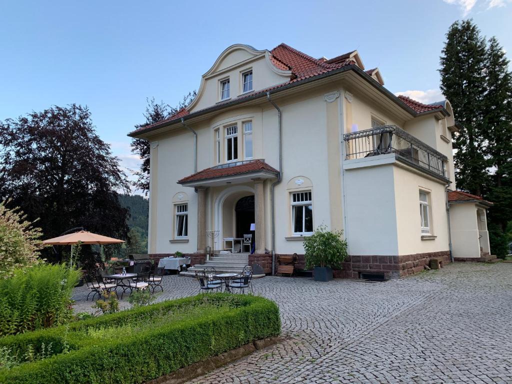 Cette grande maison blanche dispose d'une terrasse et de tables. dans l'établissement Residenz im Park, à Friedrichroda