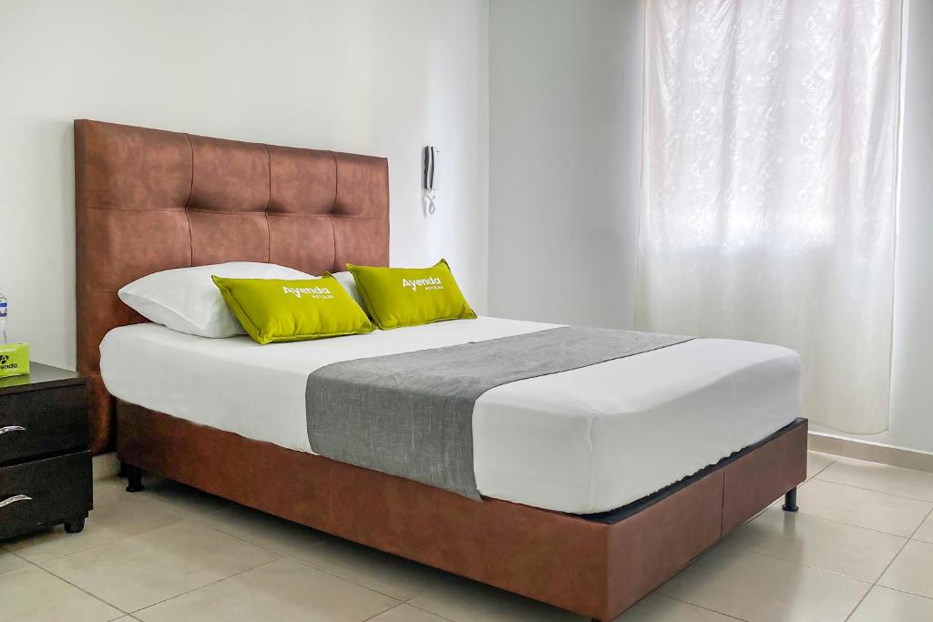 Dosquebradas的住宿－Ayenda 1138 Apartahotel 109，一间卧室配有一张大床和两张黄色枕头