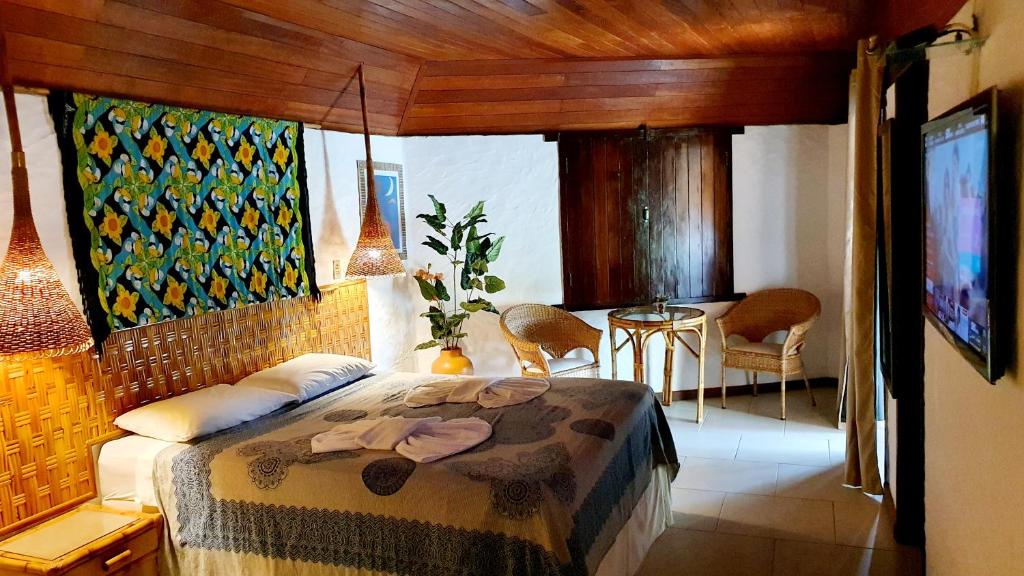 Un dormitorio con una cama y una mesa y sillas. en Pousada Entre as Águas, en Imbassai