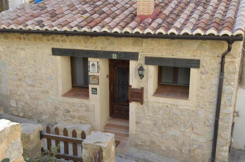 uma casa de pedra com uma porta de madeira e janelas em Casa Juan em Orihuela del Tremedal