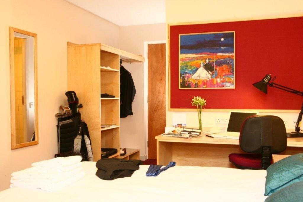 Dormitorio con cama, escritorio y pintura en David Russell Apartments - Campus Accommodation en St Andrews