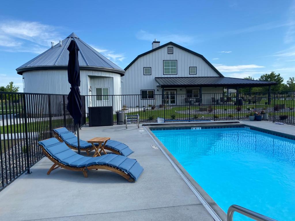 a swimming pool with two lounge chairs and an umbrella at The Barn B&B Walla Walla in Walla Walla