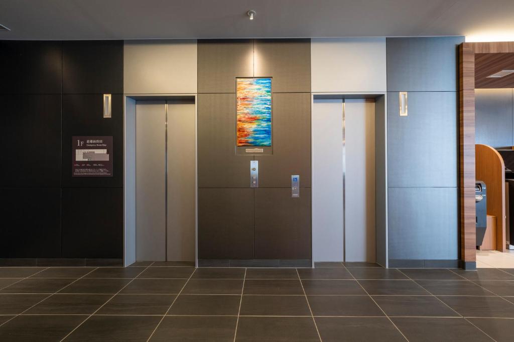a lobby with three elevators and a painting on the wall at Washington R&B Hotel Nagoya Shinkansenguchi in Nagoya
