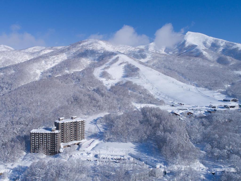 a snow covered mountain with a building in the foreground at One Niseko Resort Towers in Niseko