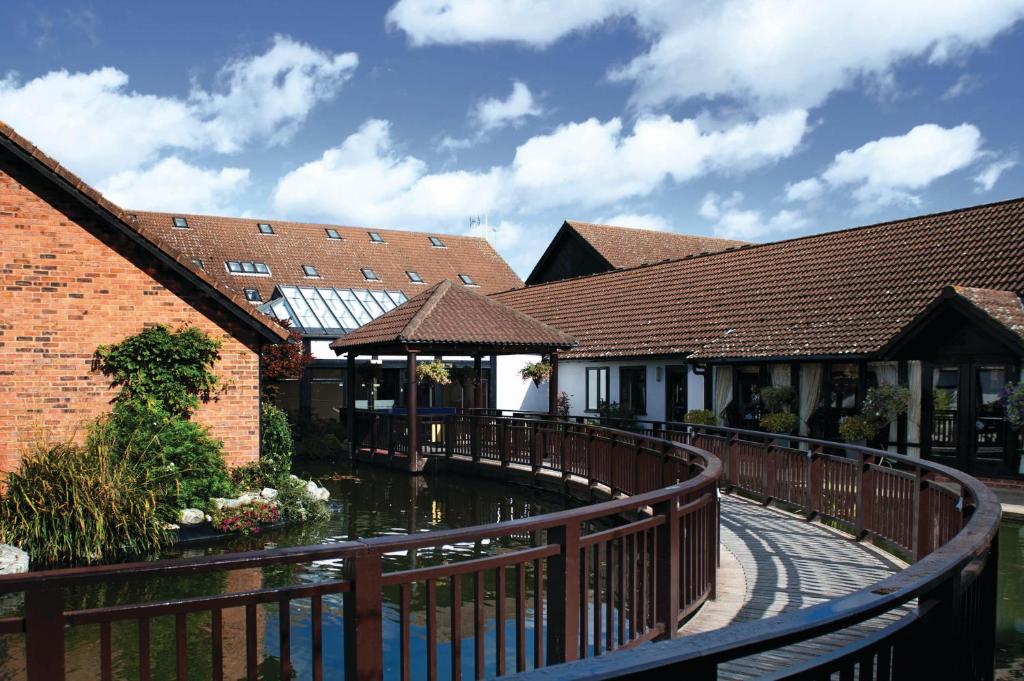 a wooden bridge over a pond in a building at Champneys Springs in Ashby de la Zouch