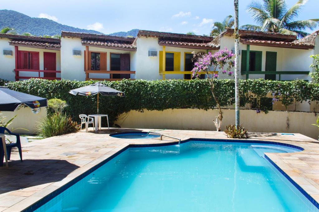 a swimming pool in front of a house at Arco Iris Chales II in Maresias