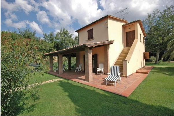 a small house with a patio and chairs on a lawn at Villa Poderino by PosarelliVillas in Bibbona