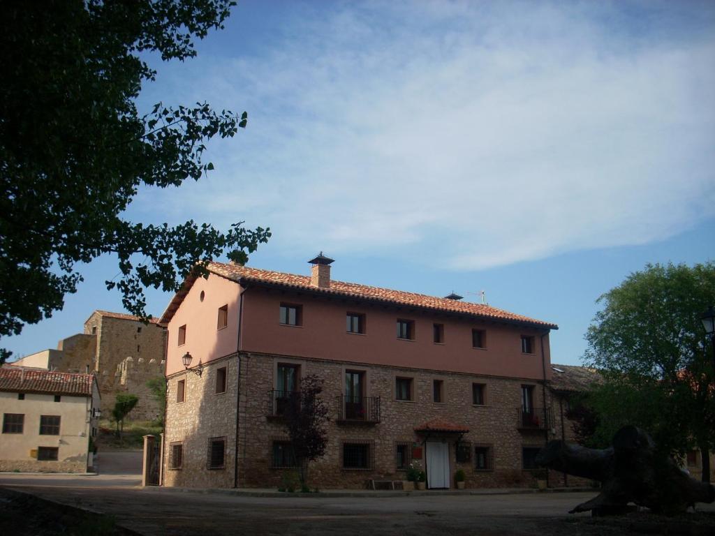 un gran edificio de ladrillo con un árbol delante de él en La Insula de Castilnuevo, en Castilnuevo