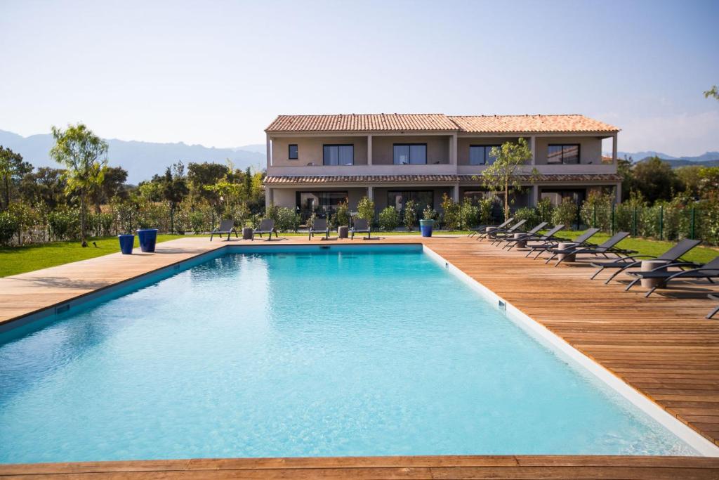 une piscine avec des chaises et une maison en arrière-plan dans l'établissement Résidence Saint Cyprien plage, à Porto-Vecchio