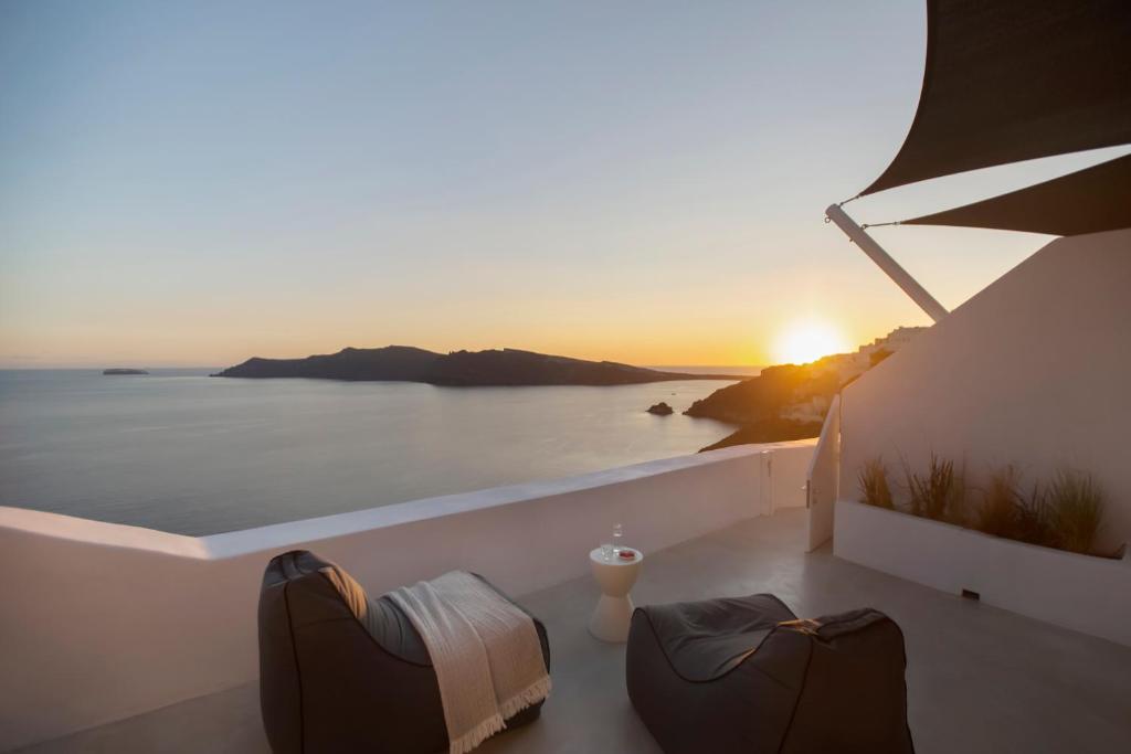 een uitzicht op de zonsondergang vanaf het balkon van een huis bij Apanema Cavehouses Santorini in Oia