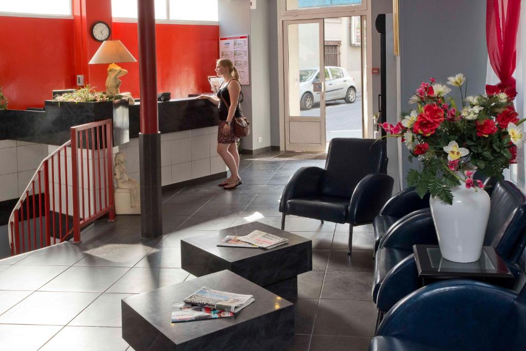 a woman standing in a waiting room at a salon at Hipotel Paris Belgrand Mairie du 20ème in Paris