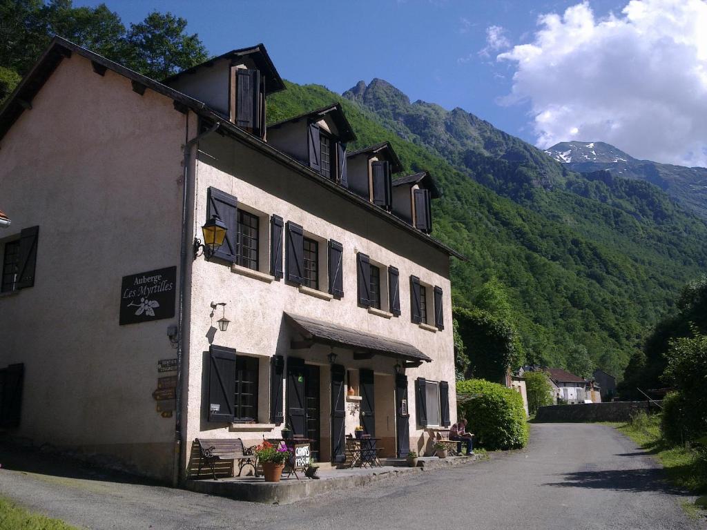 a large white building with mountains in the background at Auberge Les Myrtilles in Couflens