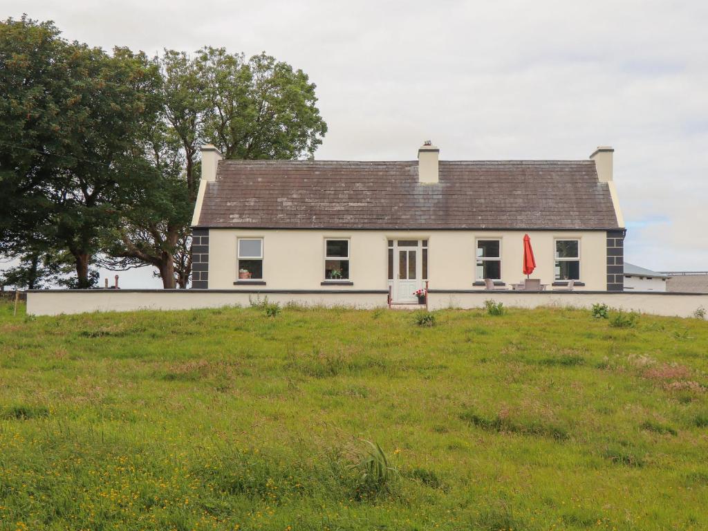 a white house on top of a grass field at Newtown East in Kilkee