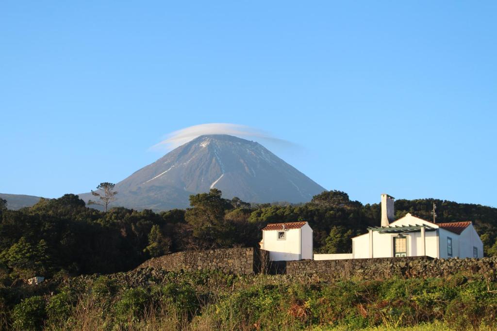 a house on a hill with a mountain in the background at Casa do Paim in São Roque do Pico