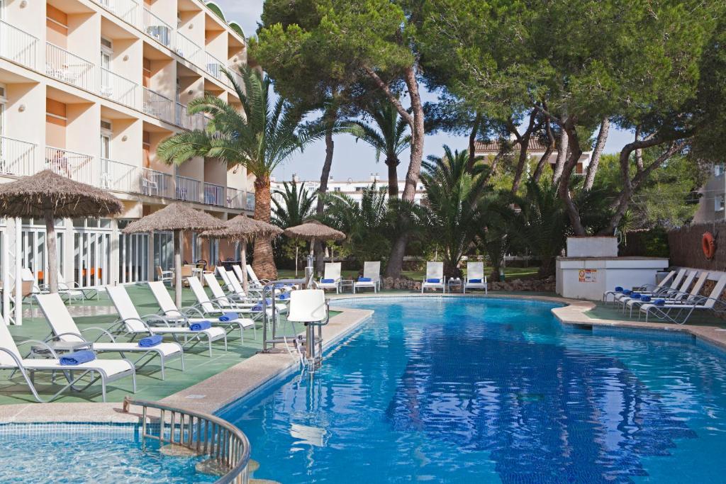 uma piscina num hotel com espreguiçadeiras e árvores em Hotel Isla de Cabrera em Colonia Sant Jordi