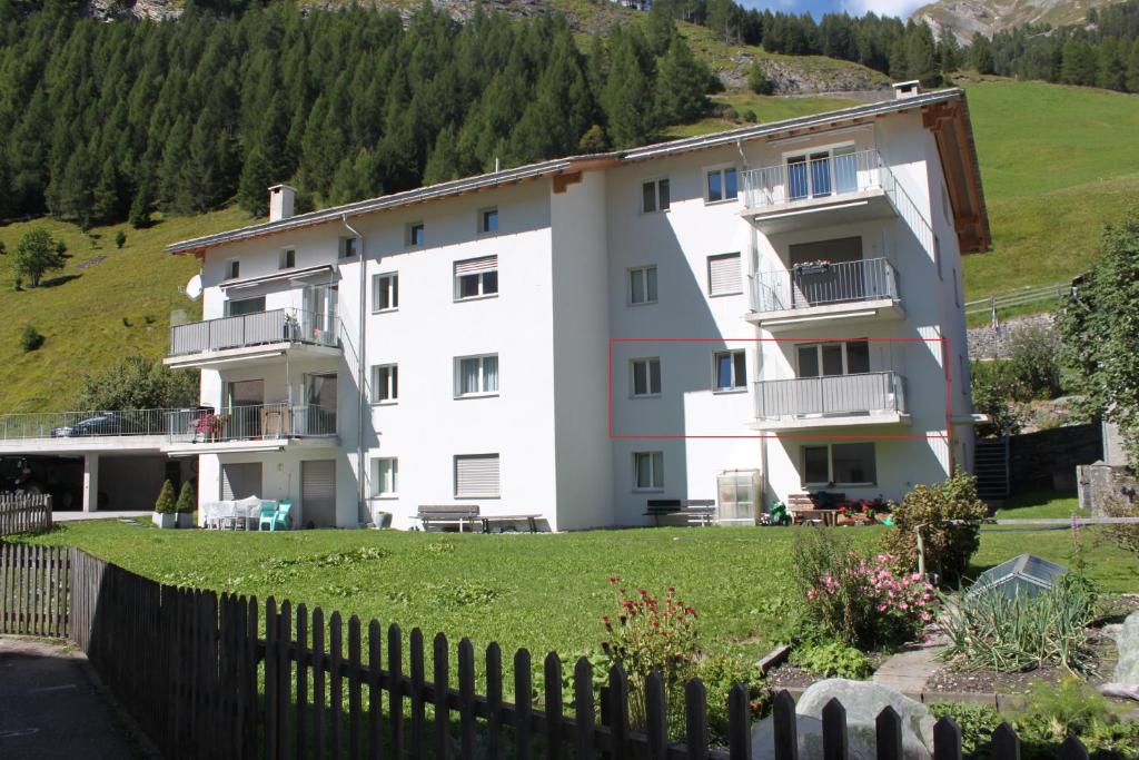 un gran edificio blanco con una valla delante en Apartment Beeli en Splügen