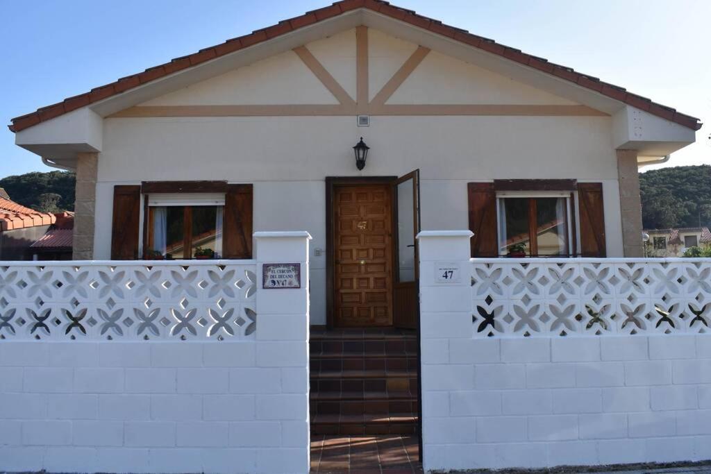 une petite maison blanche avec une clôture blanche dans l'établissement Nuevo - Cómodo y coqueto chalet con jardín en Argoños, à Argoños