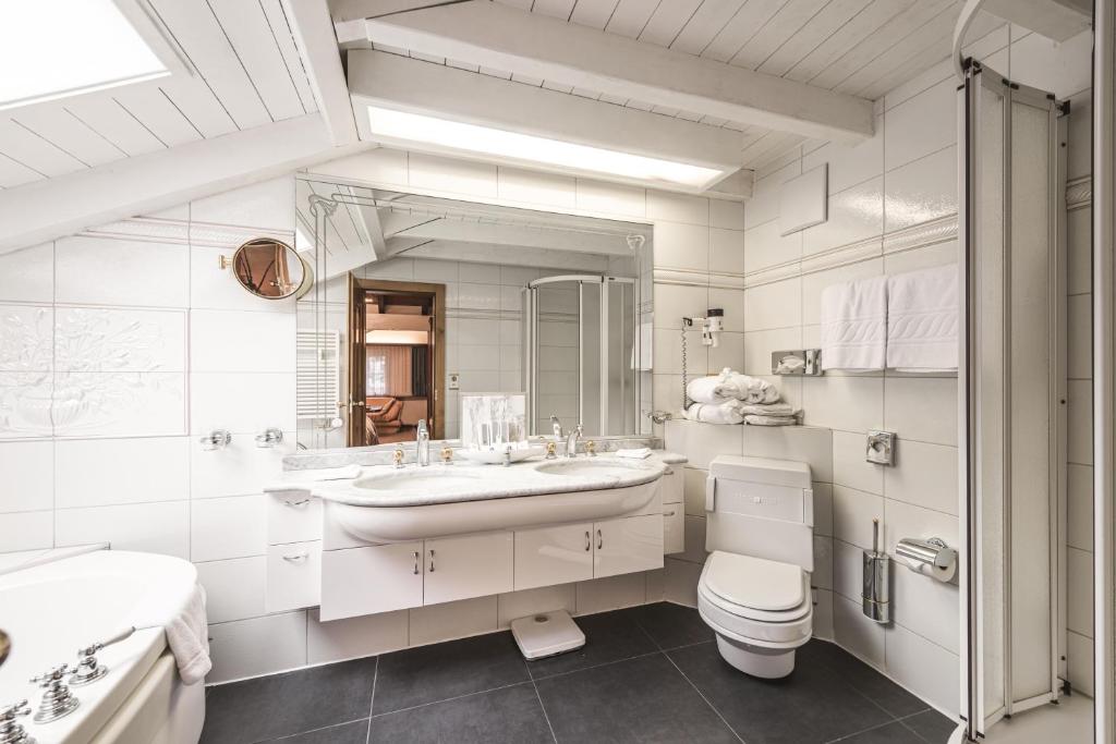 a white bathroom with a sink and a toilet at Boutique Hotel Albana Real - Restaurants & Spa in Zermatt