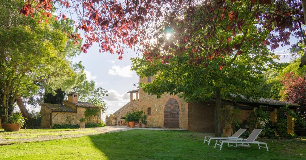 un patio con 2 sillas blancas y un edificio en Holiday Home Arpicella, en Pienza