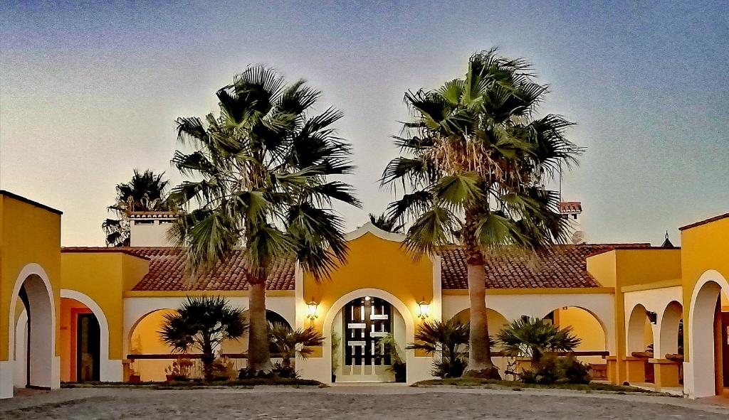 a yellow building with palm trees in front of it at Herdade da Diabroria - Agroturismo in Beringel