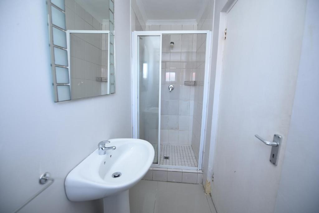 a white bathroom with a sink and a shower at The Brookston Garden Cottage in Cape Town