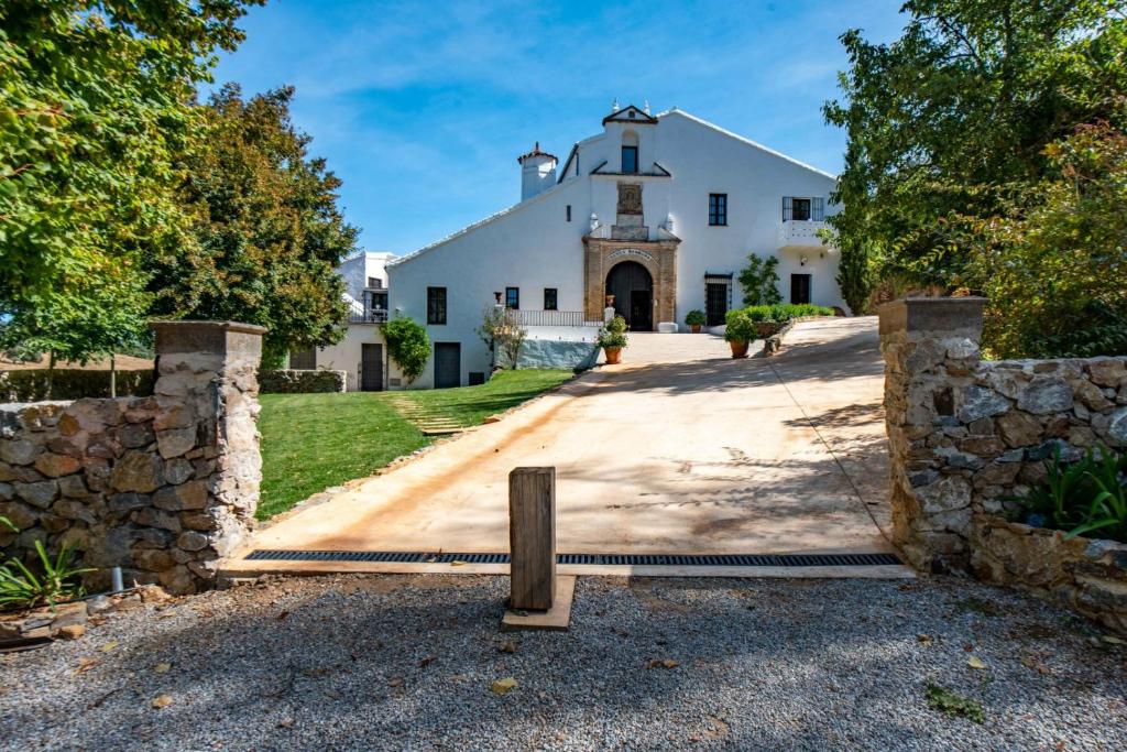 a large white house with a stone wall at Los Pozos de la Nieve in Constantina