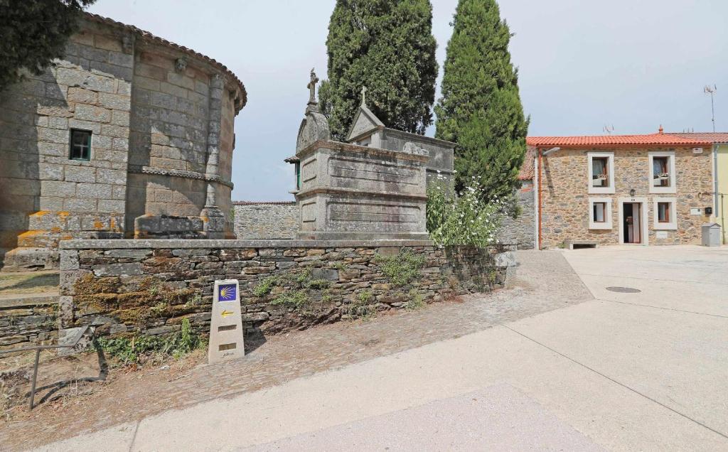 una pared de piedra con una señal frente a un edificio en Casa Santa María en Melide