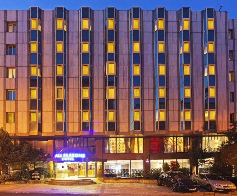 duży budynek z samochodami zaparkowanymi przed nim w obiekcie All Seasons Hotel w Stambule