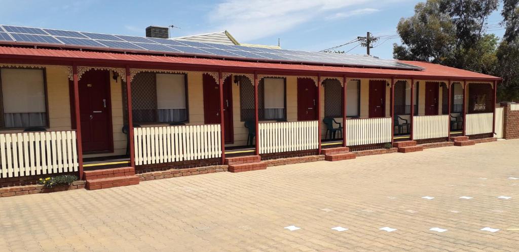 a red and white building with a solar roof at Daydream Motel and Apartments in Broken Hill