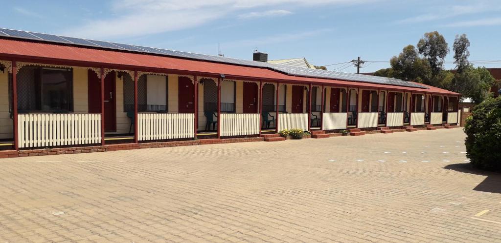 ein rotes Gebäude mit weißen Bänken auf einem Parkplatz in der Unterkunft Daydream Motel and Apartments in Broken Hill