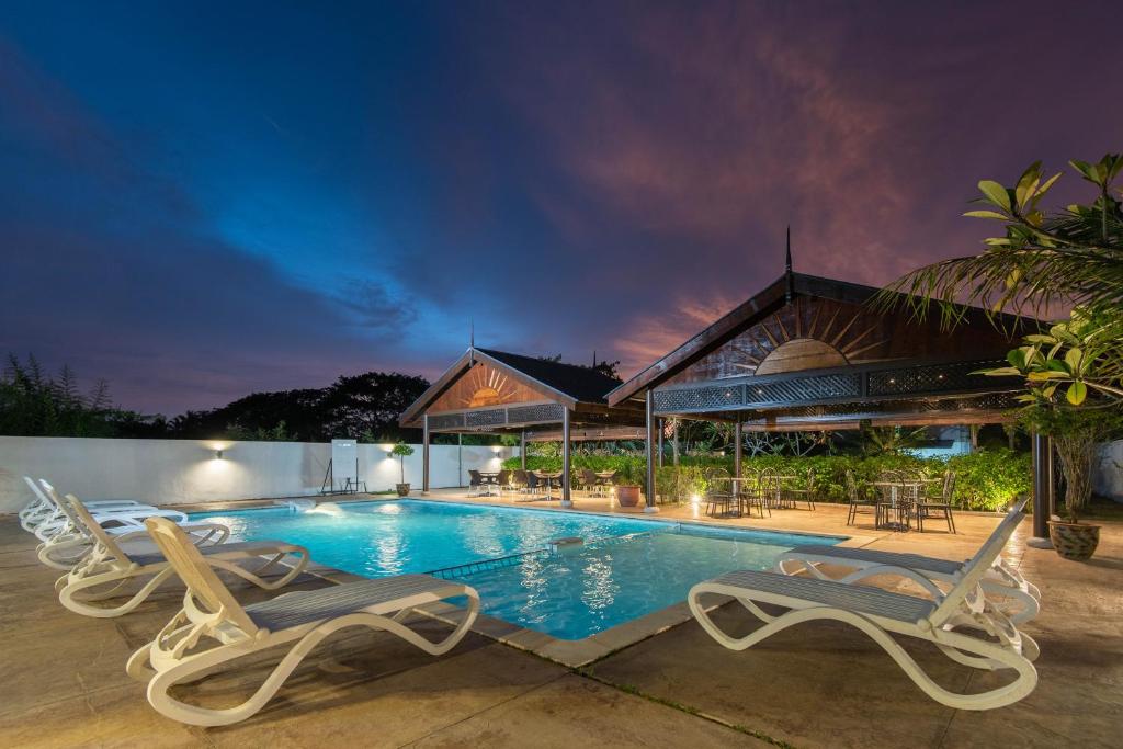 uma piscina com duas cadeiras e uma casa em Riverra Inn Langkawi em Kuah