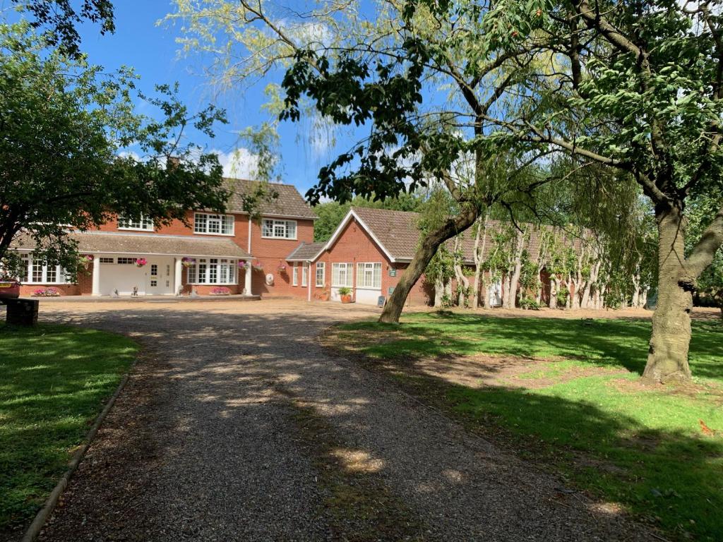 a large red brick house with trees in front of it at Aldercarr Hall in Attleborough