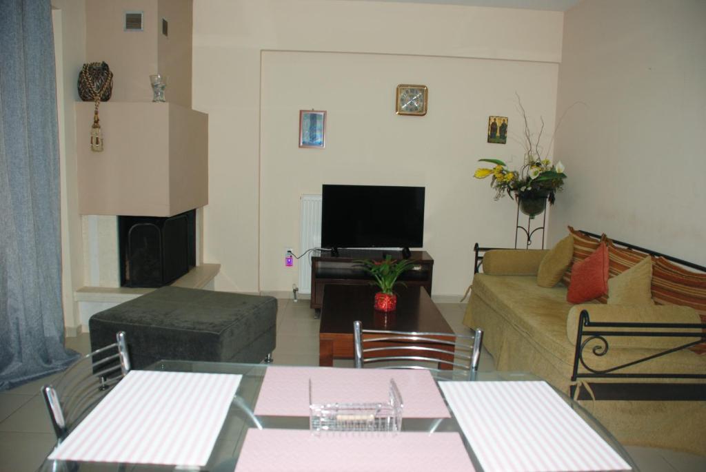 ein Wohnzimmer mit einem Sofa und einem TV in der Unterkunft Villa Maria in Ierissós
